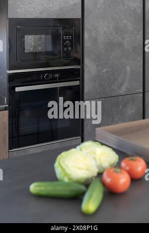 Une cuisine moderne et élégante avec des appareils électroménagers intégrés élégants, des carreaux muraux et des légumes frais sur le comptoir, capturant une maison contemporaine setti Banque D'Images