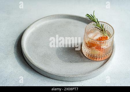 Une version moderne de la vodka tonic classique, avec une tranche de pamplemousse et une garniture de romarin, exposée sur un plateau en béton lisse Banque D'Images