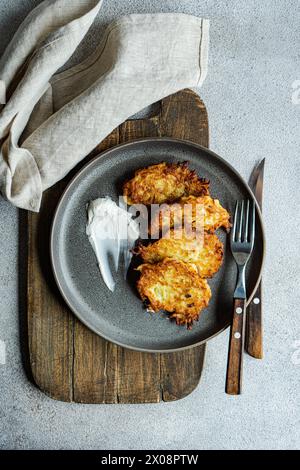 Vue de dessus des crêpes américaines salées de pommes de terre servies avec de la crème sure sur une assiette rustique, parfait pour la cuisine traditionnelle. Banque D'Images