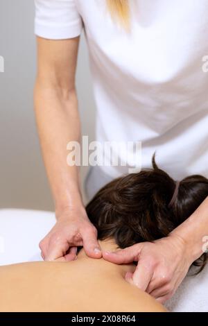 Masseuse appliquant de l'huile essentielle aromatique sur le dos d'une femme pour un massage thérapeutique dans un salon de spa Banque D'Images