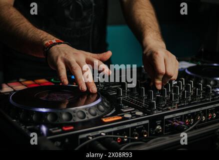 Un DJ mixe des pistes avec des mains habiles sur une console professionnelle, créant des rythmes énergiques dans un club ou un événement Banque D'Images