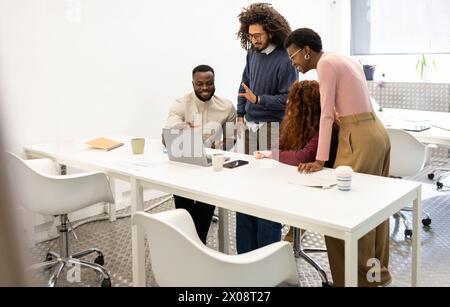 Groupe diversifié de collègues discutant d'un projet dans un environnement de bureau lumineux. Banque D'Images