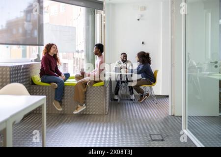 Groupe diversifié de collègues participant à une réunion informelle dans un espace de bureau bien éclairé. Banque D'Images