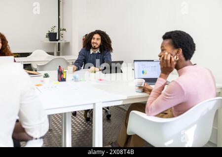 Équipe diversifiée engagée dans une réunion d'affaires dans un bureau moderne, avec un homme et une femme interagissant. Banque D'Images