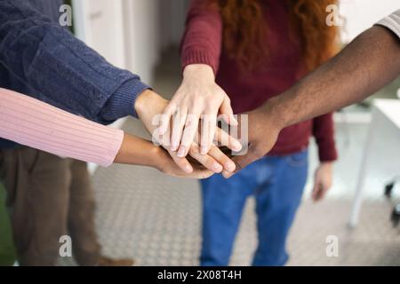 Un gros plan de plusieurs personnes méconnaissables de différentes ethnies mettant leurs mains ensemble en signe d’unité et de travail d’équipe. Banque D'Images