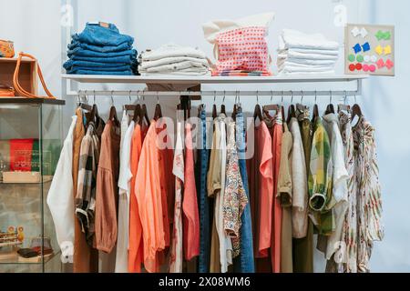 Assortiment coloré d'articles vestimentaires, y compris du denim et des vêtements à motifs, présentés sur un support métallique avec des poils soigneusement pliés sur le dessus Banque D'Images