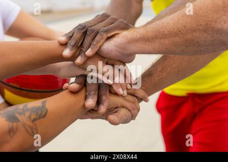 Les coéquipiers anonymes de basketball placent leurs mains ensemble dans un symbole d’unité et d’engagement partagé avant de commencer leur séance de basketball de rue Banque D'Images