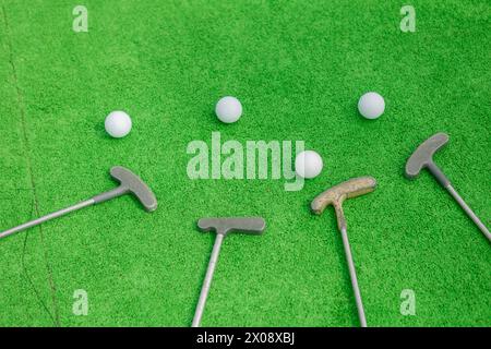 Les clubs et balles de mini-golf sont placés sur un gazon artificiel vert vibrant, indiquant un jeu agréable de mini-golf. Banque D'Images