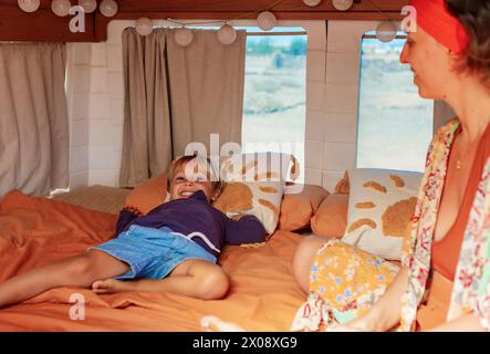 Une scène réconfortante de la vie de famille à l'intérieur d'une camionnette convertie en maison, mettant en scène un garçon ludique et sa mère avec des touches domestiques douillettes. Banque D'Images