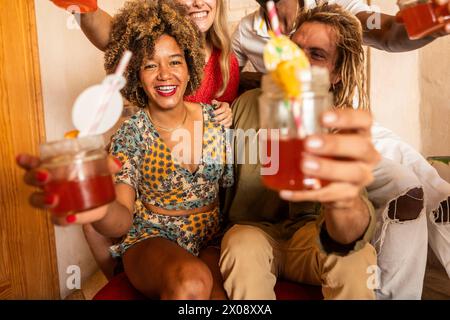 Un groupe d'amis joyeux dégustant des cocktails colorés et profitant d'une fête animée dans un cadre intime de bar Banque D'Images