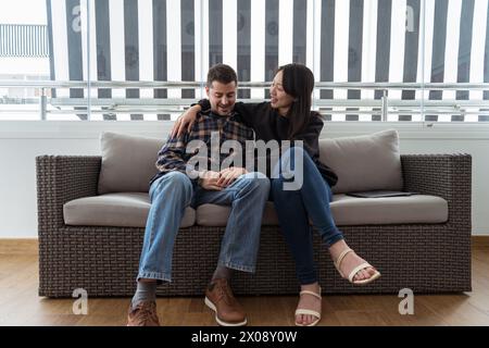 Moment intime d'un couple joyeux se relaxant ensemble sur un canapé dans un espace de vie moderne. Banque D'Images