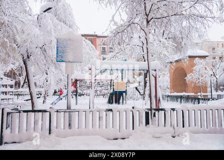 Une aire de jeux à Madrid couverte de neige épaisse, avec des arbres givrés et une atmosphère hivernale sereine. Banque D'Images