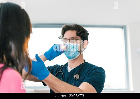 Un médecin spécialisé examine la gorge d’un patient à l’aide d’une lampe médicale, une partie essentielle d’un bilan ORL de routine Banque D'Images