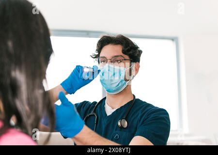 Un médecin spécialisé examine la gorge d’un patient à l’aide d’une lampe médicale, une partie essentielle d’un bilan ORL de routine Banque D'Images