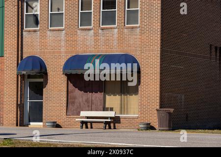Un banc vacant se trouve devant la fenêtre arborée d'un vieil immeuble en briques dans le centre-ville de Big Stone Gap, Virginie Banque D'Images
