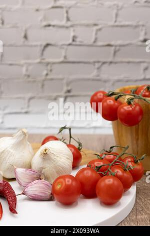 ingrédients dans la cuisine, tomates cerises de vigne avec de l'ail et du poivre frais sur une planche de bois et du mortier pour hacher Banque D'Images