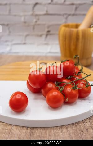 ingrédients dans la cuisine, tomates cerises de vigne sur une planche de bois et de pierre et mortier pour hacher Banque D'Images