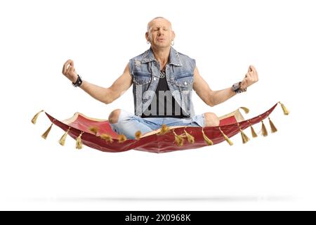 Homme chauve assis à jambes corssées et pratiquant la méditation sur un tapis magique isolé sur fond blanc Banque D'Images
