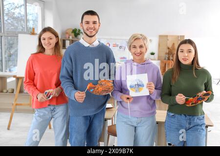 Professeur d'art mature et étudiants avec des peintures à l'école Banque D'Images