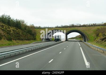 Un camion est vu conduire dans un tunnel sur une autoroute achalandée avec d'autres véhicules en mouvement. Banque D'Images