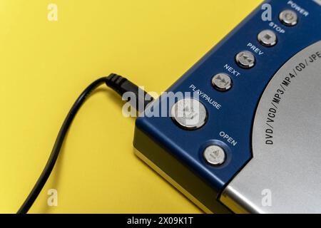 Vue détaillée d'un lecteur CD, d'un lecteur DVD placé sur une table jaune, présentant des boutons, un écran d'affichage et une surface réfléchissante. Banque D'Images