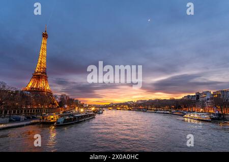 Tour Eiffel au coucher du soleil, avec le paysage urbain parisien en arrière-plan et la rivière Sena. Banque D'Images