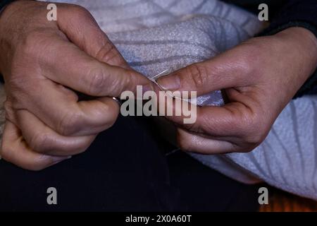 Vue rapprochée des mains de la femme dans le processus de couture. Tissu à coudre à la main avec aiguille sur le lieu de travail. Mains de couturière tenant le tissu pour la fabrication Banque D'Images