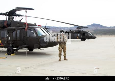 Soldat de l’armée américaine de l’Alpha Co, 2e escadron, 916e bataillon d’aviation (2916e AVN BN) “Desert Hawks”, stationné au premier National Training Center (NTC) à Fort Irwin, Calif, se tient devant un UH60 (hélicoptère Blackhawk) avant d’exécuter un survol du match de football LA Galaxy le 25 février 2024, au Dignity Health Sports Park à Carson, Calif. Banque D'Images