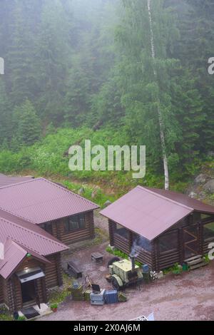 Cuisine militaire de terrain sur roues près des bâtiments dans la forêt dans le brouillard Banque D'Images