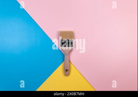 Vue de dessus du pinceau sur fond coloré. Fond bleu, rose et jaune. Papier peint coloré, pose à plat, espace de copie. Banque D'Images