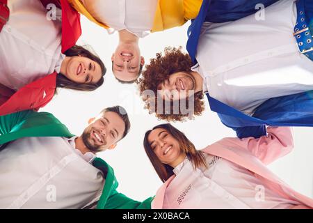 Cercle d'amis blottis ensemble regardant vers le bas vers la caméra avec des sourires éclatants. Banque D'Images