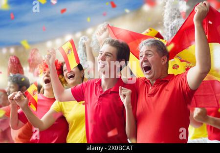 Un supporter de football espagnol sur le stade. Les fans espagnols sur le terrain de football regardant l'équipe jouer. Groupe de supporters avec drapeau et maillot national acclamations Banque D'Images