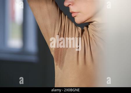 Image rapprochée de la femme en col roulé en coton beige avec patch de sueur sous l'aisselle Banque D'Images