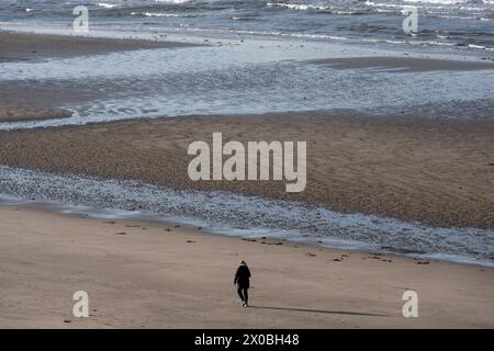 Une femme marche seule sur la plage de sable. Banque D'Images