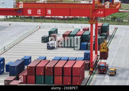 SUQIAN, CHINE - 11 AVRIL 2024 - Une grue soulève des conteneurs sur un camion au port de canal Suqian à Suqian, province du Jiangsu, Chine, le 11 avril 2024. IT Banque D'Images