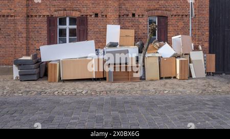 Pile de déchets encombrants avec des meubles sur le côté de la route devant une maison Banque D'Images