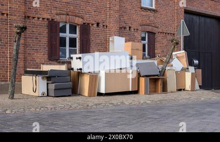 Pile de déchets encombrants avec des meubles sur le côté de la route devant une maison Banque D'Images