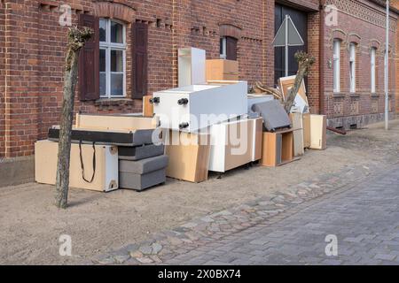 Pile de déchets encombrants avec des meubles sur le côté de la route devant une maison Banque D'Images