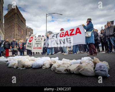 6 avril 2024, Brooklyn, États-Unis : un petit groupe de manifestants tient des banderoles et des pancartes alors qu’ils entourent plusieurs simulations de cadavres d’enfants lors d’une manifestation pro-palestinienne. Les manifestants se rassemblent à Grand Army Plaza à Brooklyn pour protester contre le meurtre d'enfants à Gaza. Ils ont rejoint les Jewish Elders & Friends pour Ceasefire, une partie de Jewish Voice for Peace. L'accent a été mis sur le fait d'exhorter le sénateur Schumer à cesser d'armer le génocide avec le slogan «nous exigeons de l'action, pas des mots vides». La route a traversé le marché de farmerâ€™ pour mettre en évidence l'impact de la famine sur les enfants palestiniens. Banque D'Images