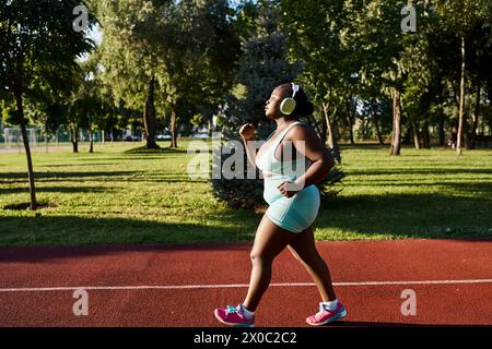 Une femme afro-américaine en vêtements de sport, célébrant ses courbes, court gracieusement sur un court de tennis dans un cadre extérieur. Banque D'Images