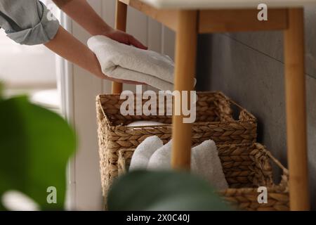 Femme mettant la serviette dans le panier de rangement à l'intérieur, gros plan Banque D'Images