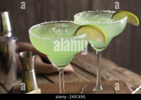 Délicieux cocktail Margarita avec des glaçons dans des verres et citron vert sur une table en bois, gros plan Banque D'Images