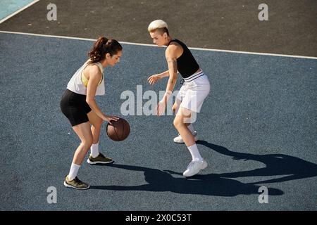 Deux jeunes femmes athlétiques jouant au basket-ball sur un terrain extérieur en été. Banque D'Images