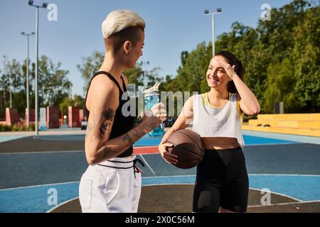 Un homme et une femme se tiennent en toute confiance sur un terrain de basket-ball, mettant en valeur leur athlétisme et leur travail d'équipe dans un jeu animé. Banque D'Images