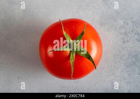 Une tomate rouge sur un fond bleu clair, vue de dessus Banque D'Images