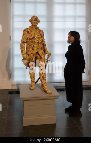 LONDRES, ROYAUME-UNI - 11 AVRIL 2024 : un membre du personnel regarde “Clive”, “structures décolonisées” (2022-23) composé de sept sculptures en fibre de verre de personnages coloniaux, peintes à la main avec un motif de cire hollandaise lors d’un appel photo pour l’exposition “Suspended States” de Yinka Shonibare à Serpentine South à Londres, Royaume-Uni, le 11 avril 2024. La première exposition personnelle du travail de Shonibare dans une institution publique londonienne depuis plus de 20 ans explore les thèmes centraux des héritages du pouvoir colonial, des lieux de refuge et d’abri ainsi que l’impact écologique de la colonisation, l’héritage européen d’imper Banque D'Images