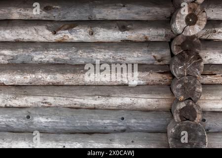 Vieux mur de maison en bois fait de bûches grises rugueuses, texture de fond Banque D'Images