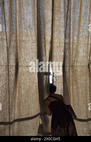 Femme en silhouette regardant à travers un rideau de crème solaire, qui protège les dîners de restaurant de café de trop de lumière directe du soleil. Elle regarde la place Saint-Marc. Piazza San Marco. Années 2009 2000 Venise Italie HOMER SYKES Banque D'Images