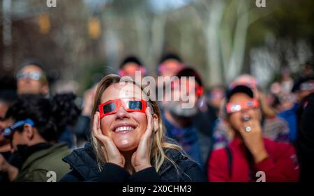 Des centaines de personnes se rassemblent à Flatiron Plaza à New York pour une fête d'observation à regarder, portant leurs lunettes de protection, l'éclipse solaire le lundi 8 avril 2024. New York City n'était pas sur le chemin de la totalité avec la lune couvrant 89% du soleil pendant la fenêtre de 15h15 à 15H30. (© Richard B. Levine) Banque D'Images