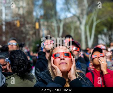 Des centaines de personnes se rassemblent à Flatiron Plaza à New York pour une fête d'observation à regarder, portant leurs lunettes de protection, l'éclipse solaire le lundi 8 avril 2024. New York City n'était pas sur le chemin de la totalité avec la lune couvrant 89% du soleil pendant la fenêtre de 15h15 à 15H30. (© Richard B. Levine) Banque D'Images